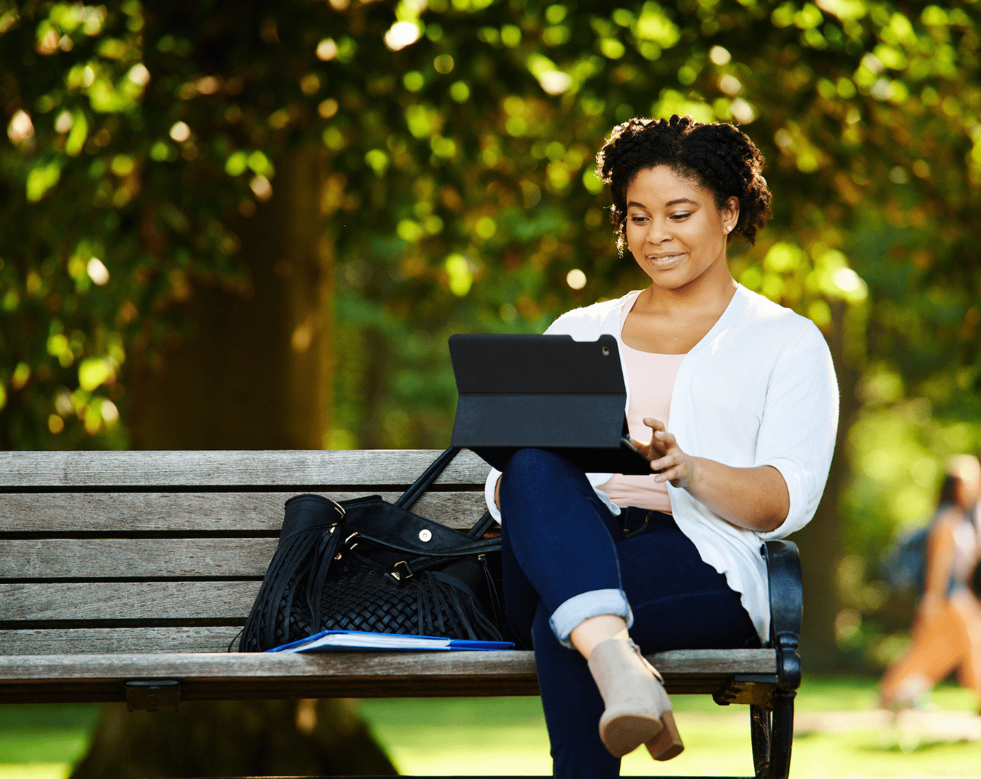 A student sitting on a bench with a tablet. 